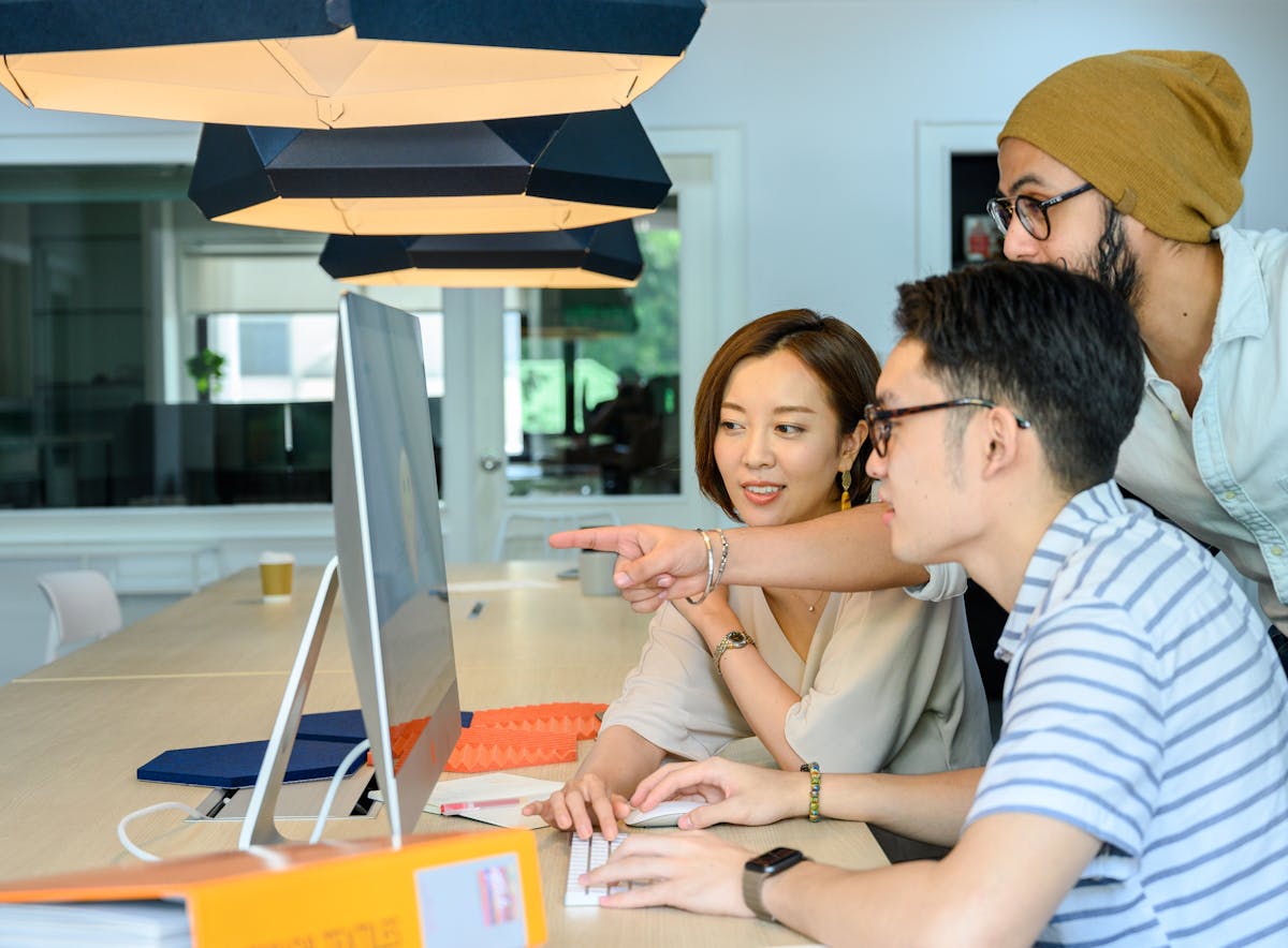 Team of professionals gathered around a computer in a modern office